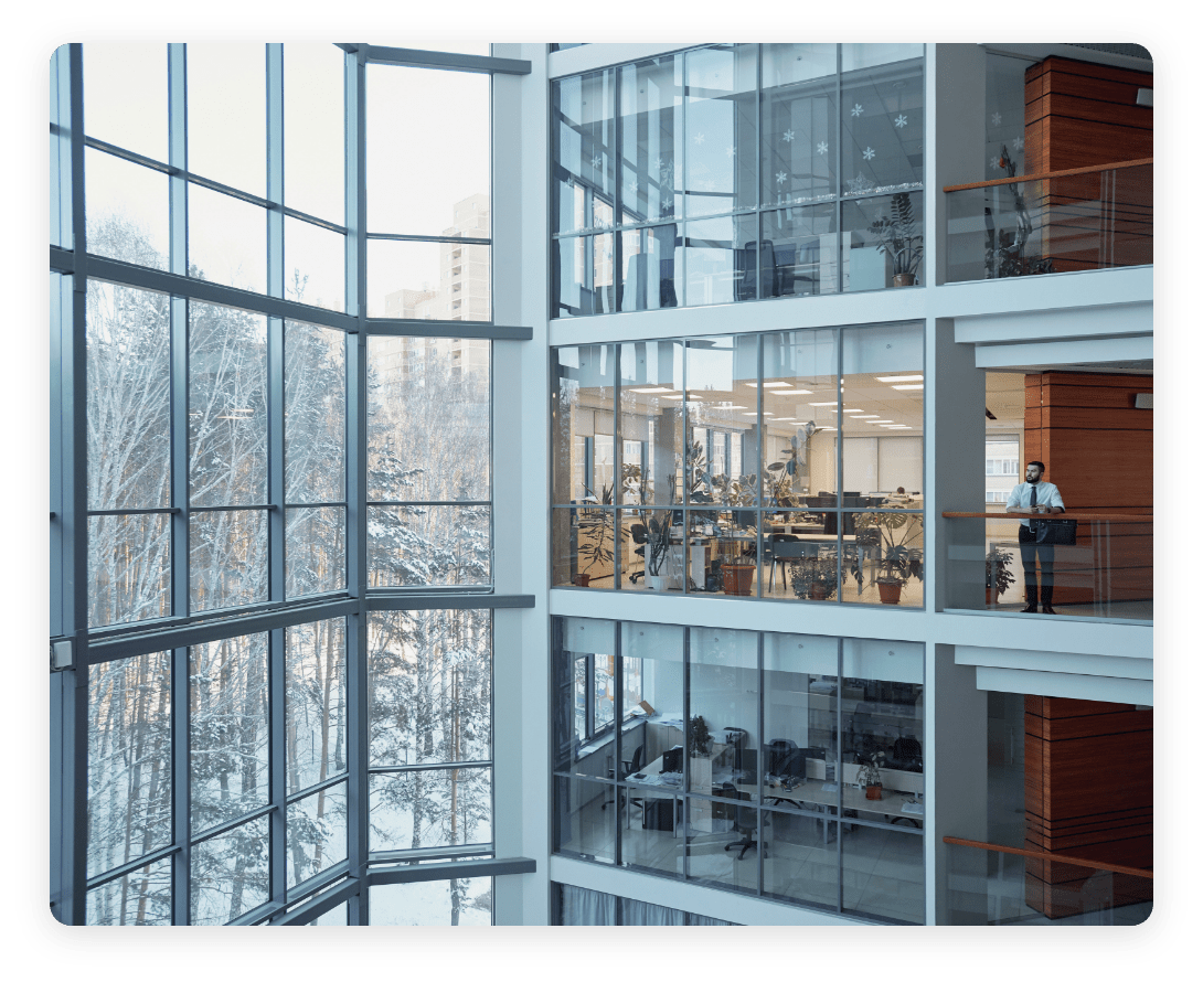 Interior view of a modern office with large glass walls, showcasing workplace environments that can benefit from occupancy intelligence for efficient space management.